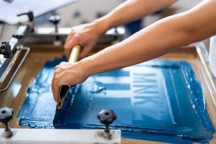 A person is using a screen printing machine to print a sign.