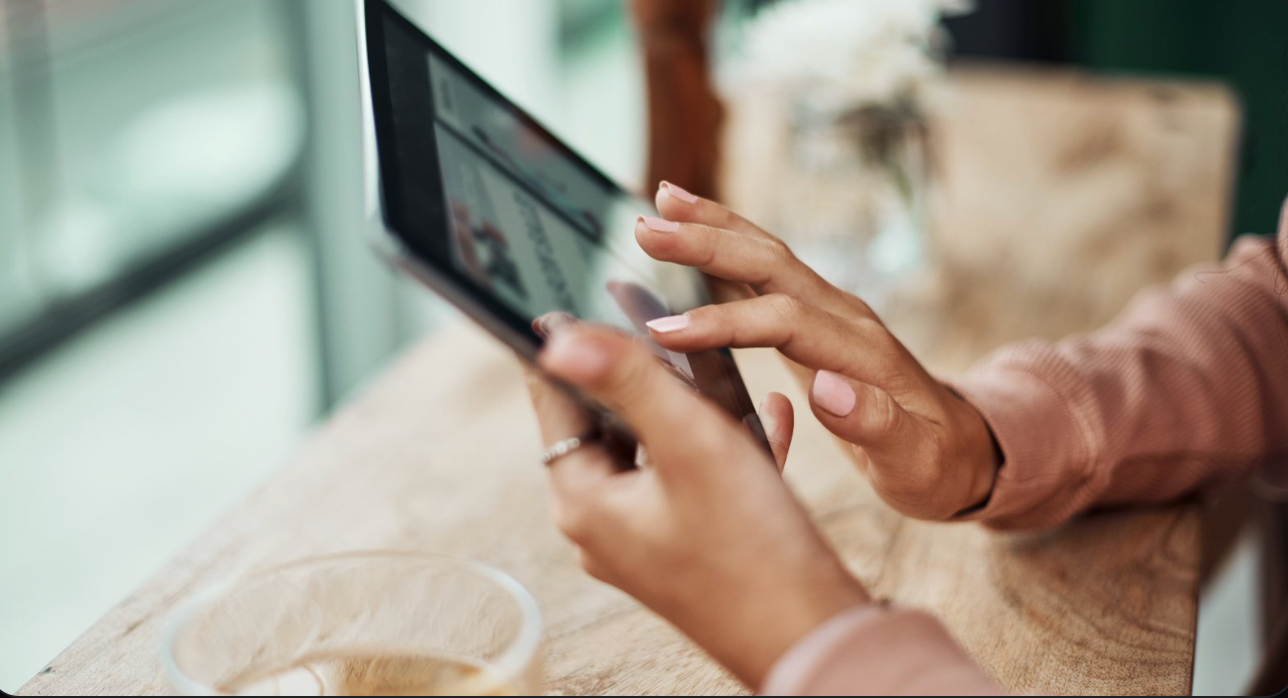 Hands using a tablet on a table in a bright room