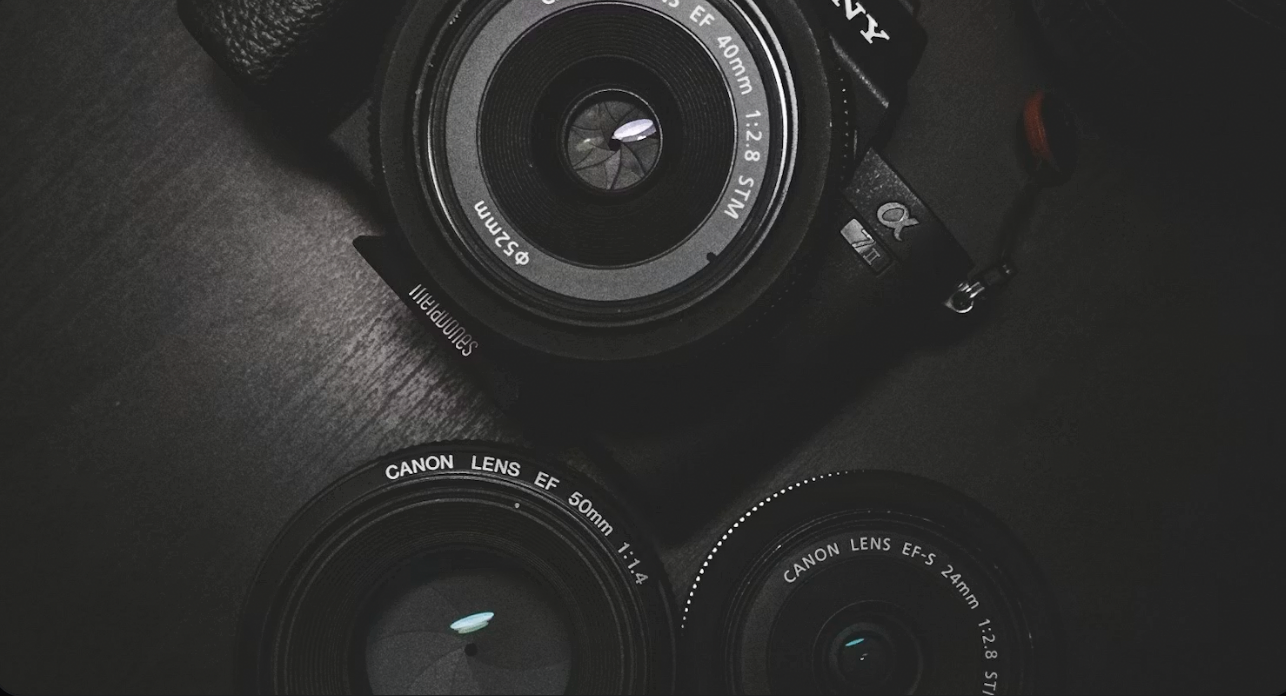 Three cameras on a dark surface, with one camera centered and two lenses below