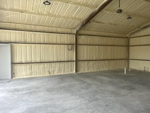 Empty metal-walled warehouse with a concrete floor and a large roll-up door on the left.