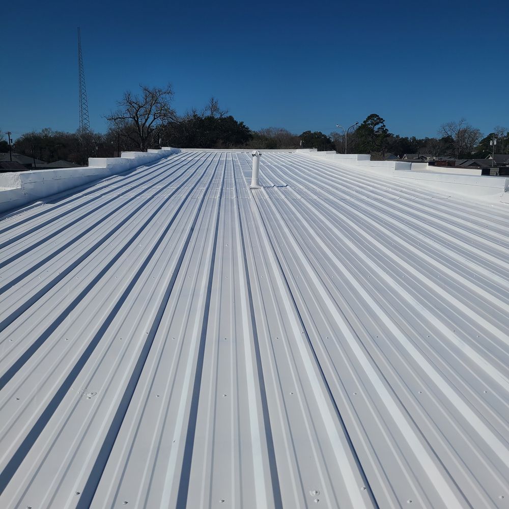 White corrugated metal roof under a clear blue sky, viewed from the rooftop ridge