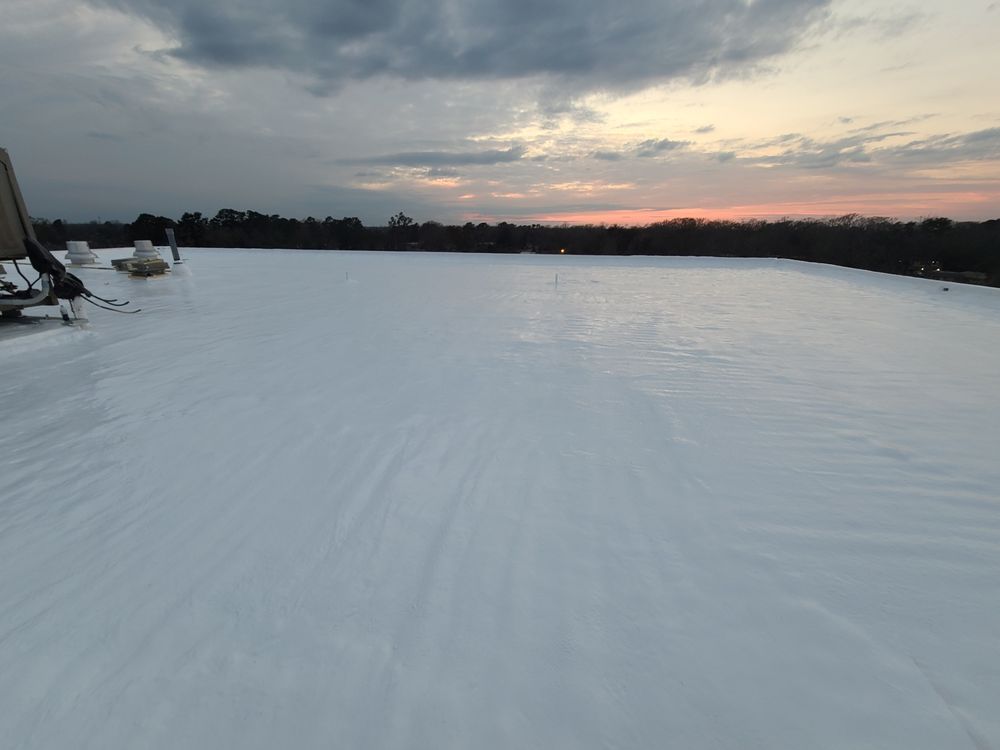 Snow-covered frozen lake at sunset with a dark treeline and pink clouds on the horizon