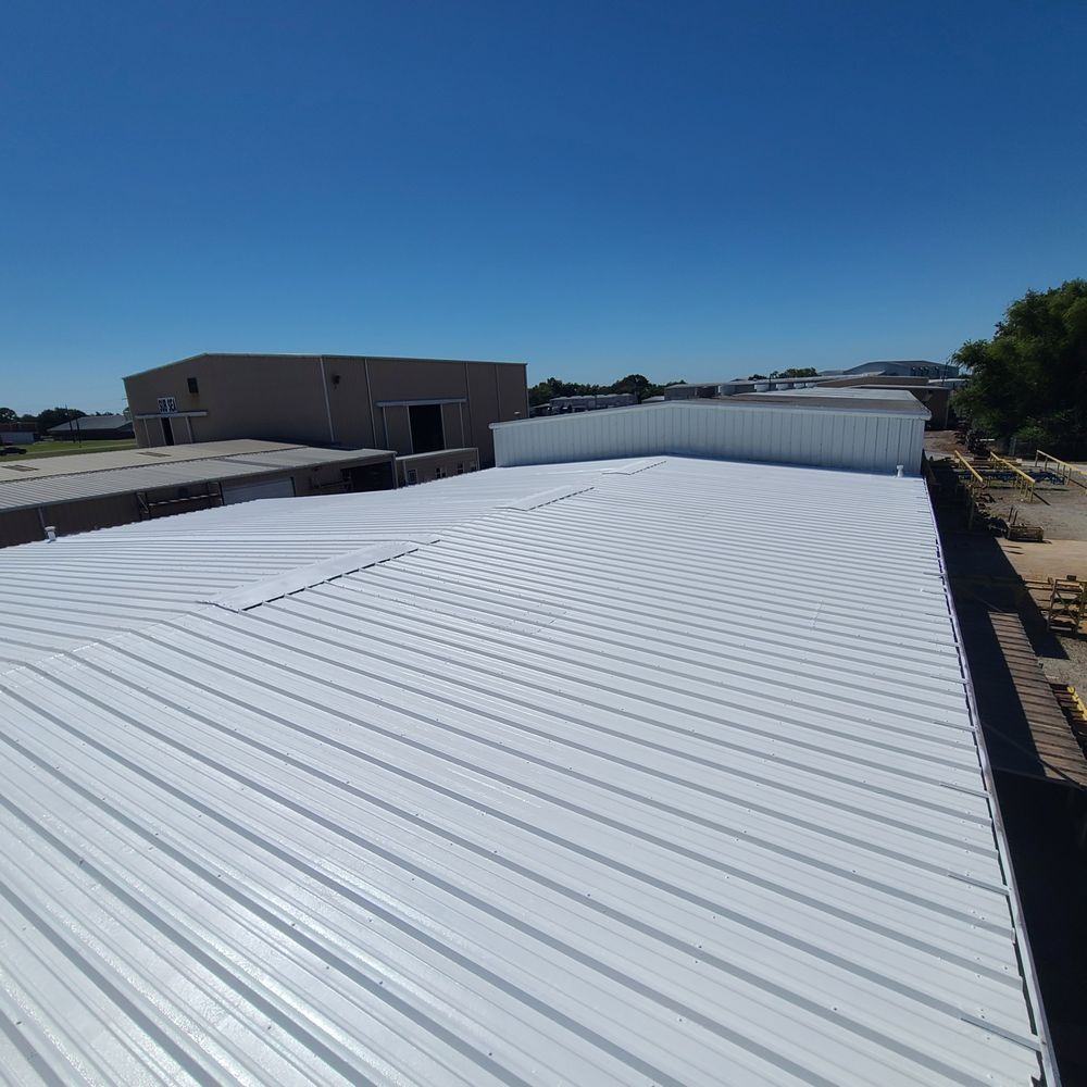 White corrugated metal roof on an industrial building under a clear blue sky