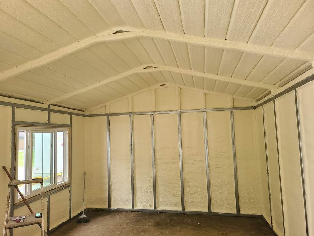 Unfinished room interior with insulated white walls, exposed framing, and a vaulted ceiling.