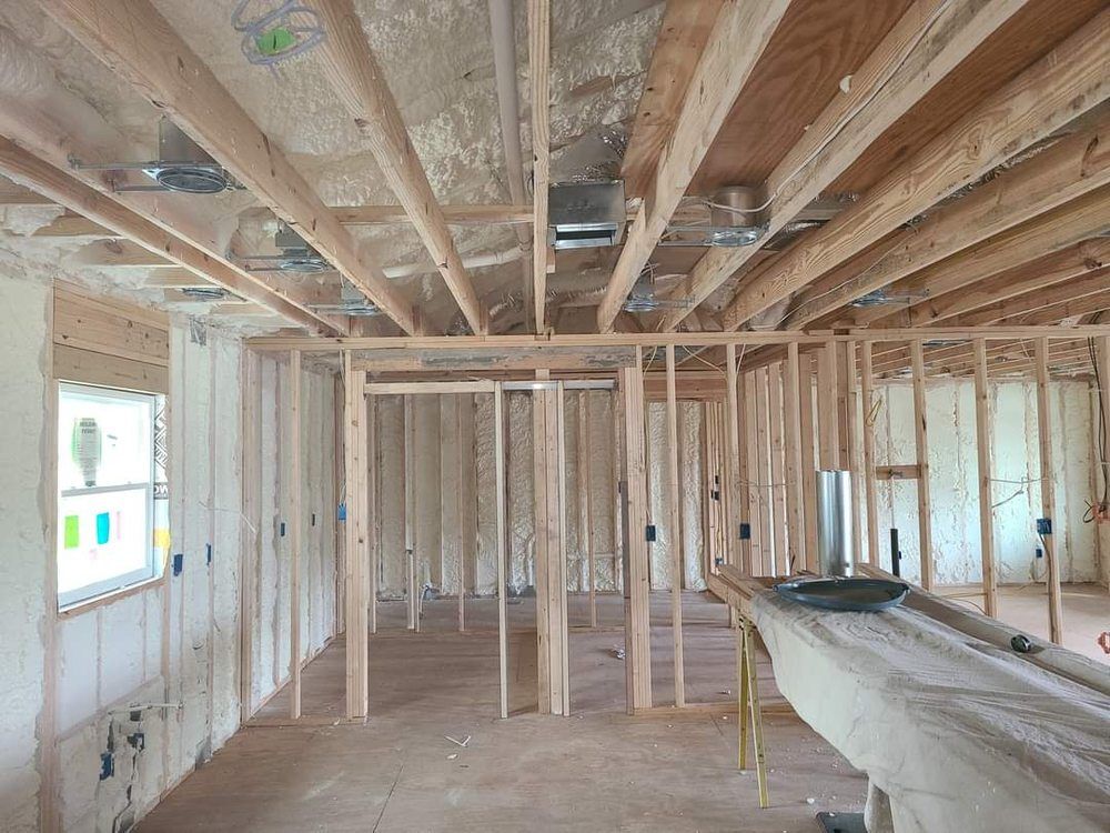 Interior of an unfinished wooden house framing with exposed studs, beams, and floor joists.