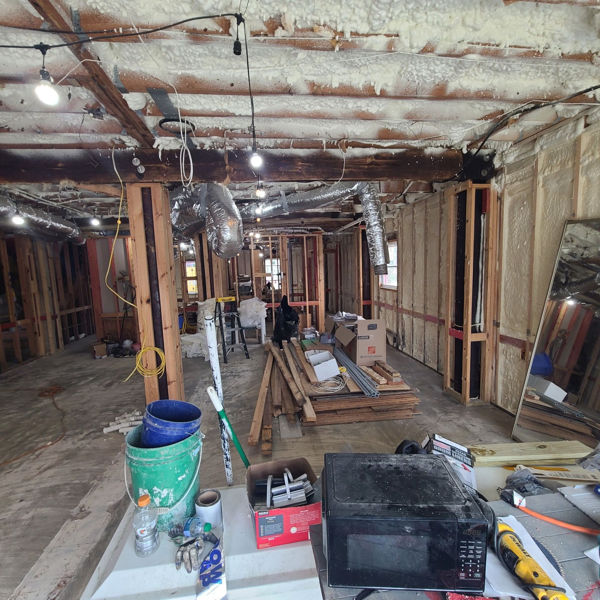 Partially renovated basement with exposed framing, insulation, tools, and construction materials scattered about