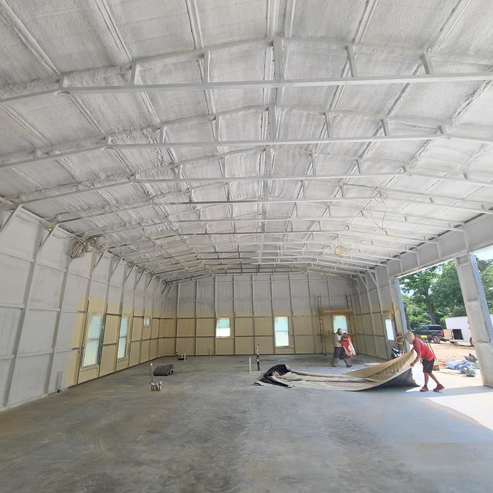 Workers installing flooring inside a large warehouse with a high arched ceiling
