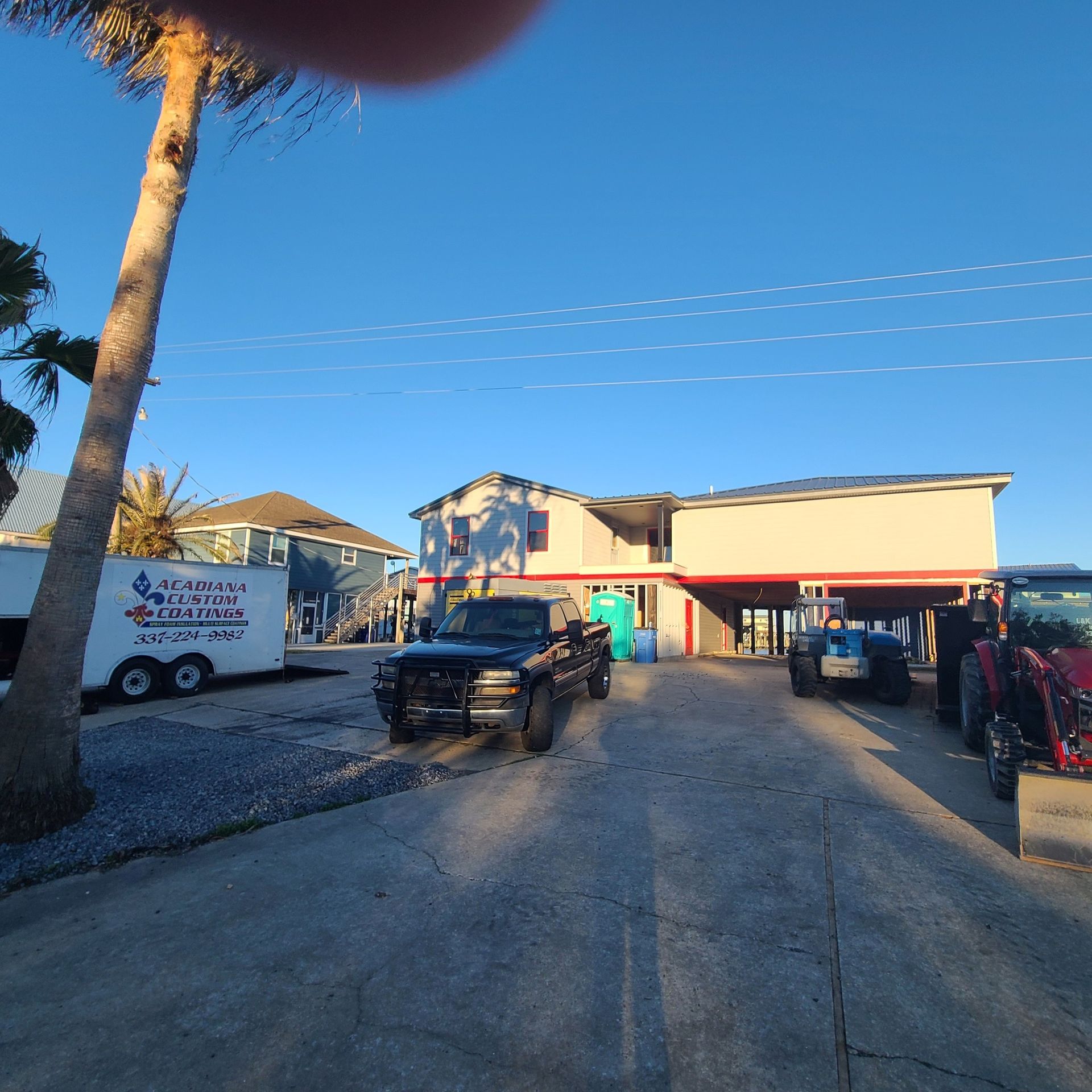 Street view of a small storefront with parked cars and a palm tree under a clear blue sky
