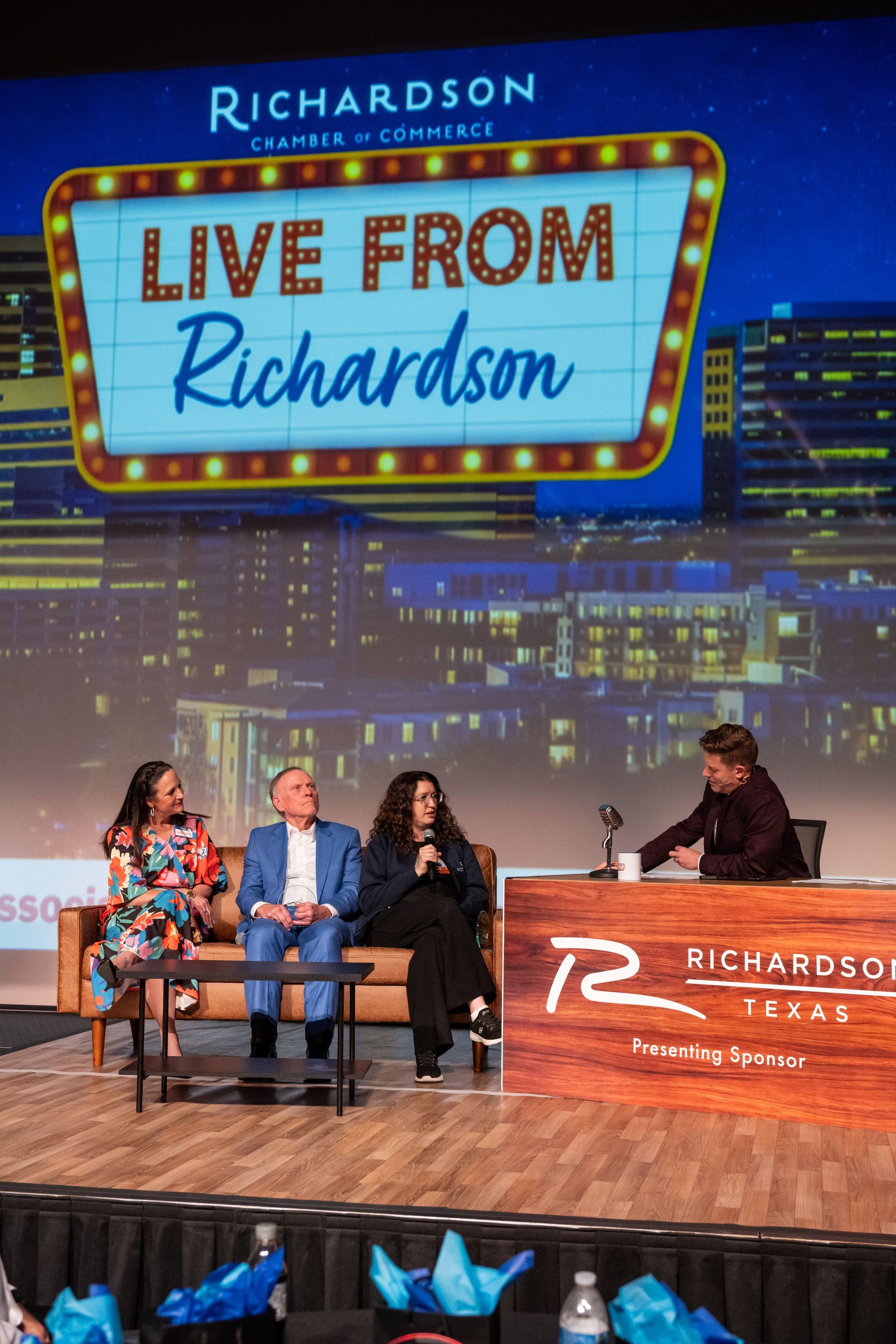 A panel of four people sits on a stage for a