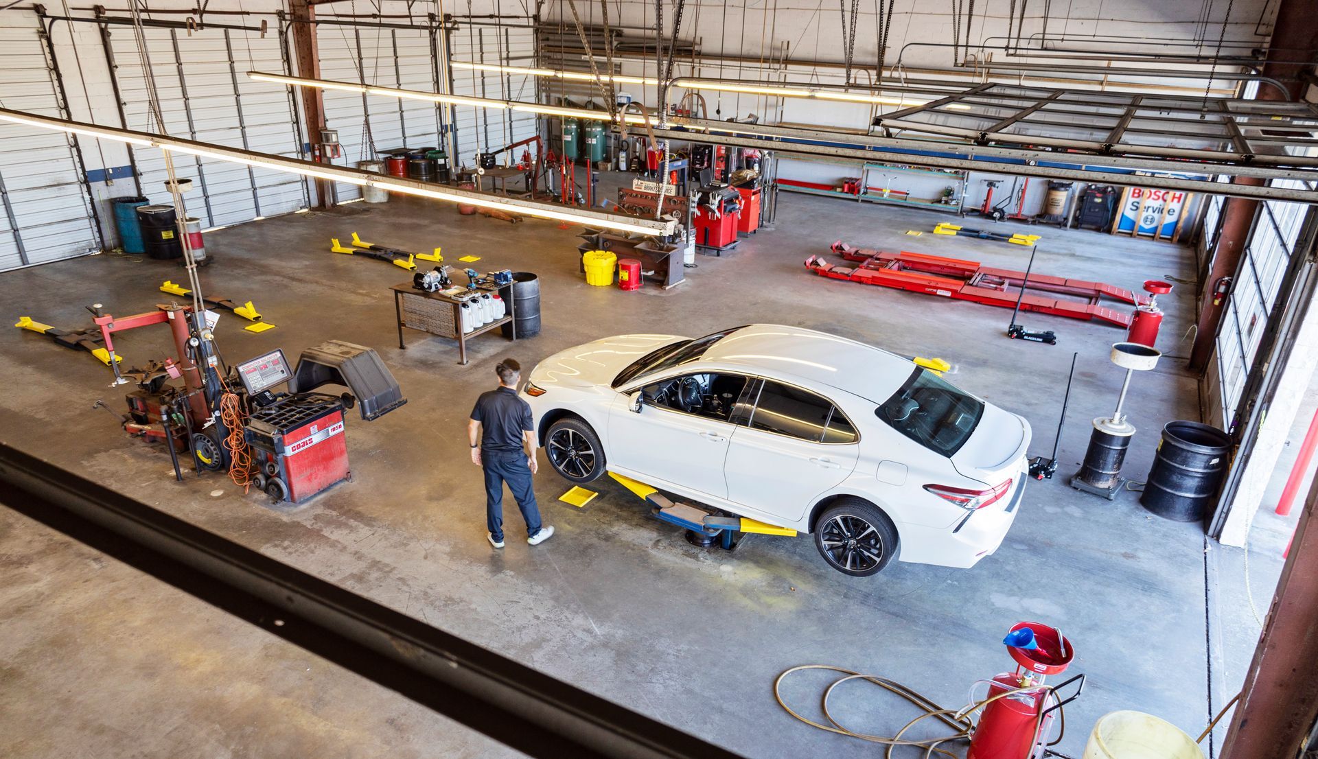 Overhead view of an AAMCO Repair Center with a technician looking at a white car