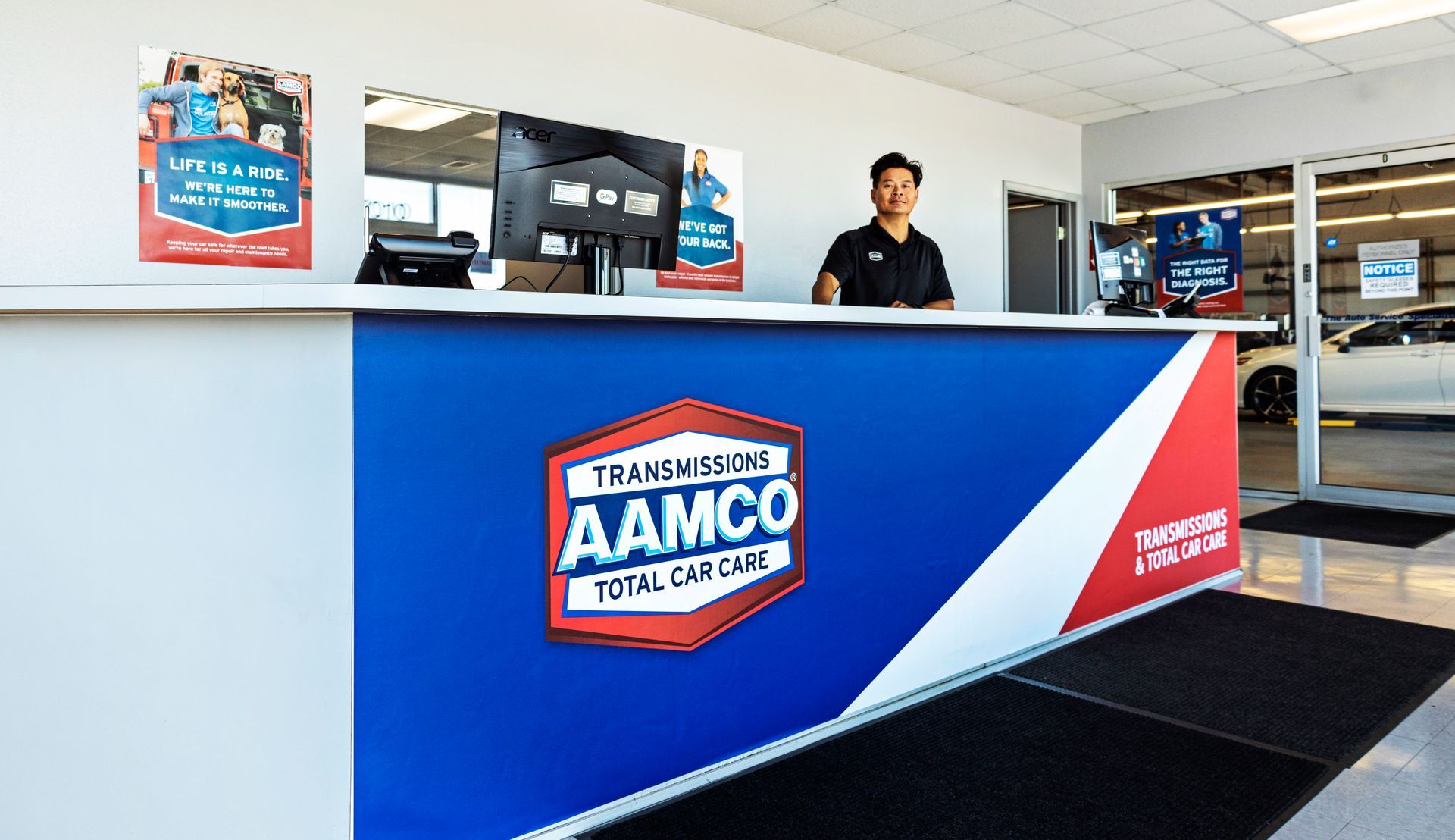 Inside view of an AAMCO Service Center lobby in Port Richey, FL. with a technician standing behind the front desk