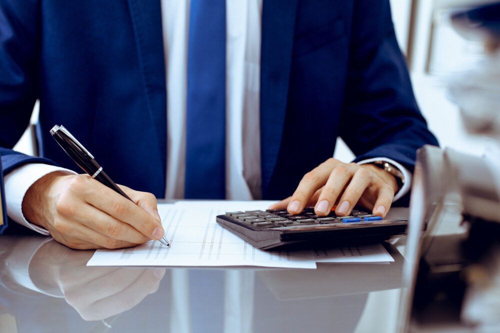 A Man in a Suit is Writing on a Piece of Paper While Using a Calculator — Darwin BAS n Books In Palmerston, NT