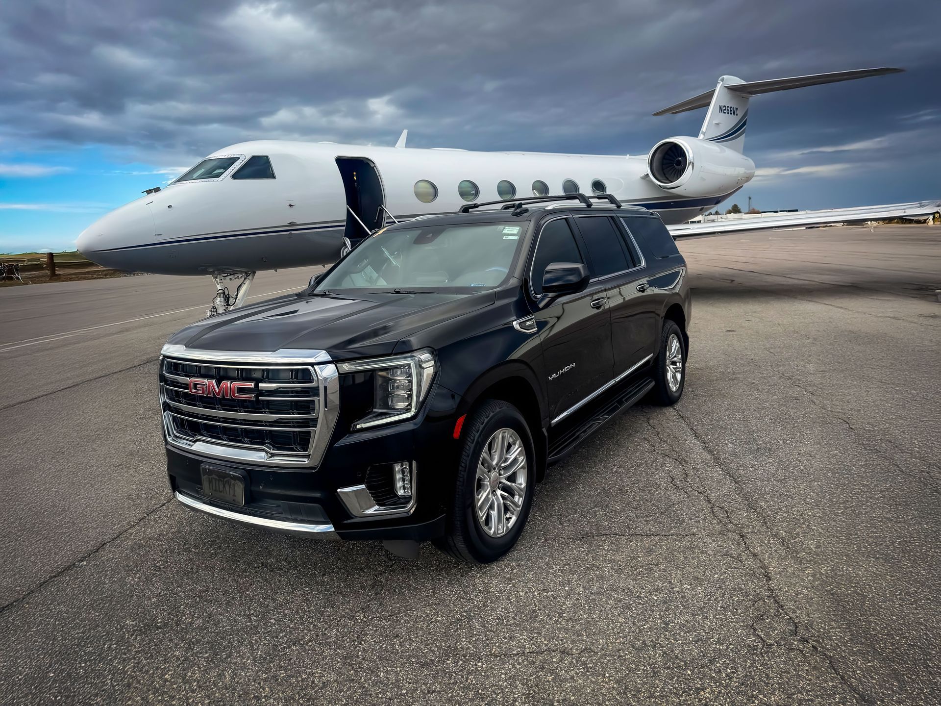 Black SUV parked on tarmac in front of a private jet at an airport