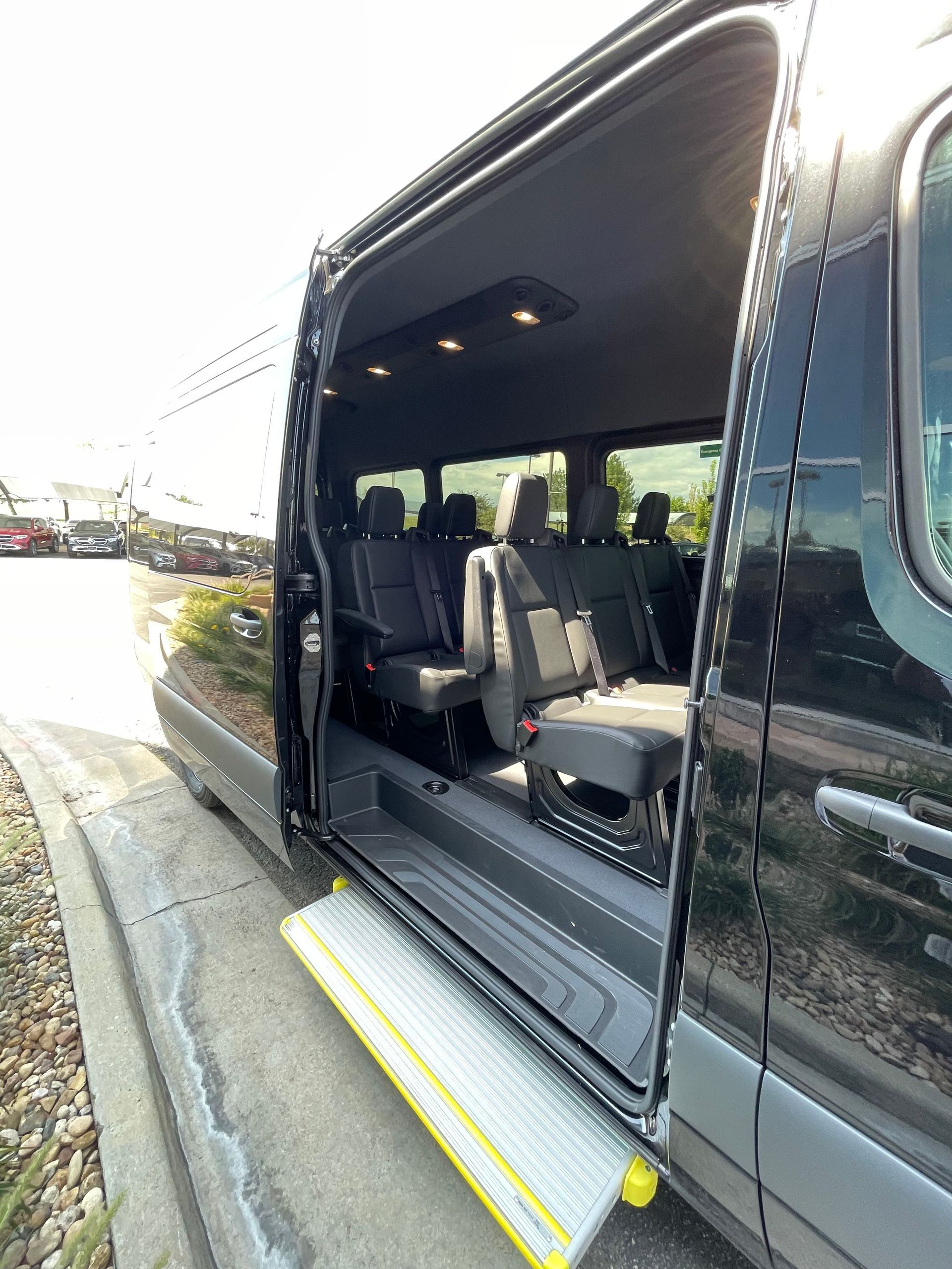 Open van with sliding door open, showing gray seats and wheelchair lift at the curb.