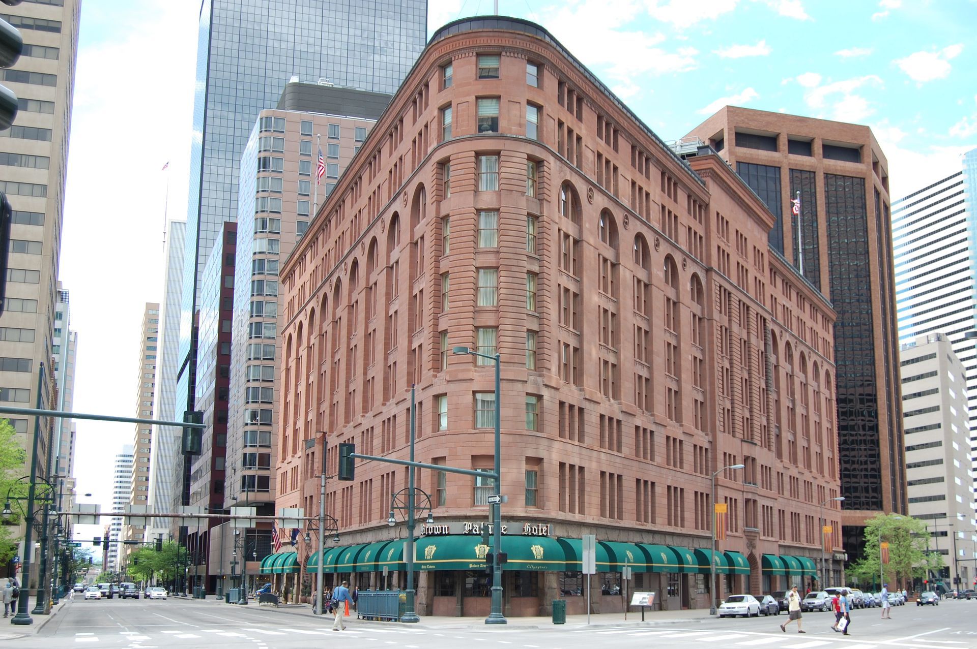 Historic red-brick office building with green awnings on a city street corner.