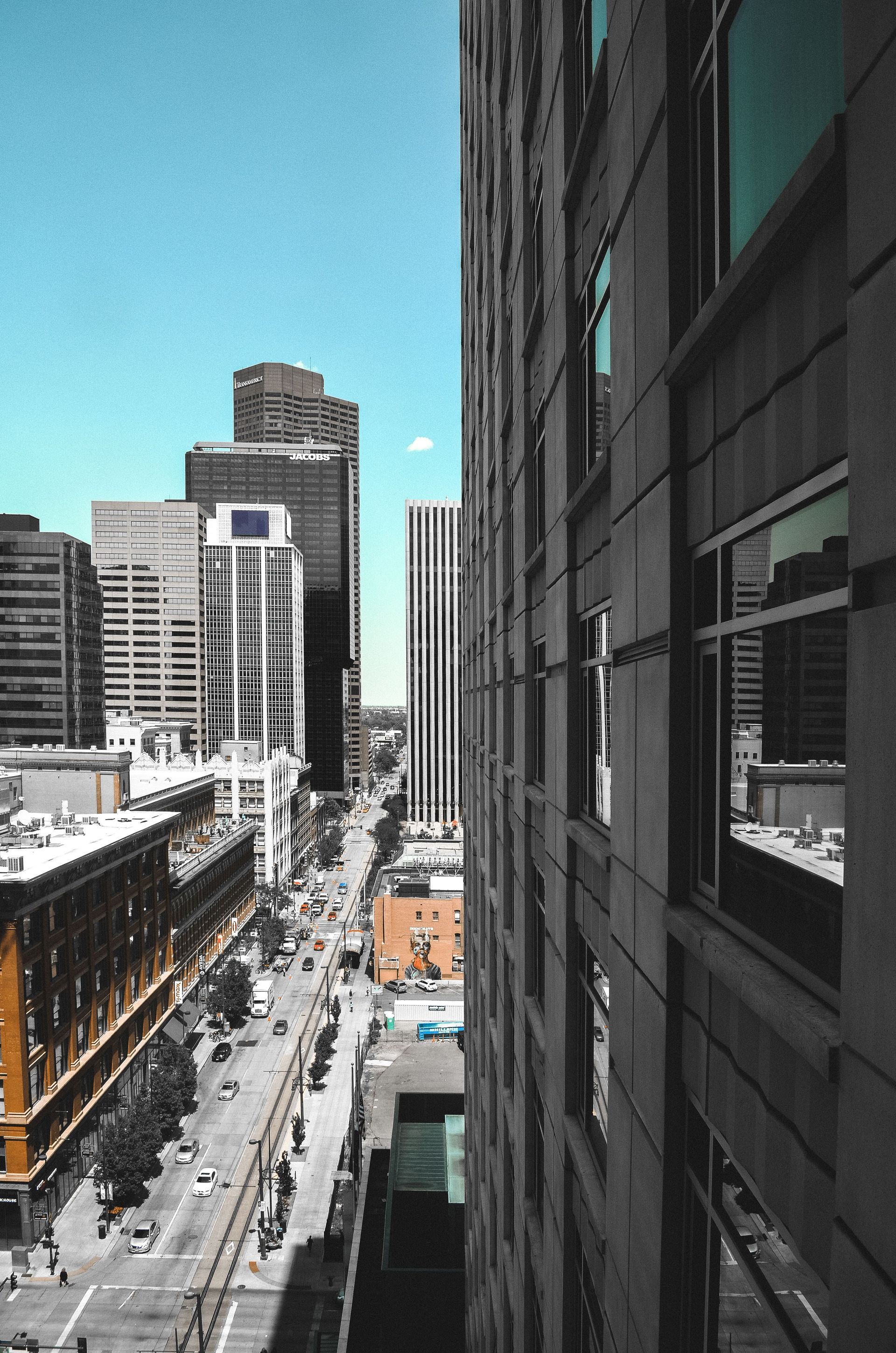 Tall city street between high-rise buildings under a bright blue sky