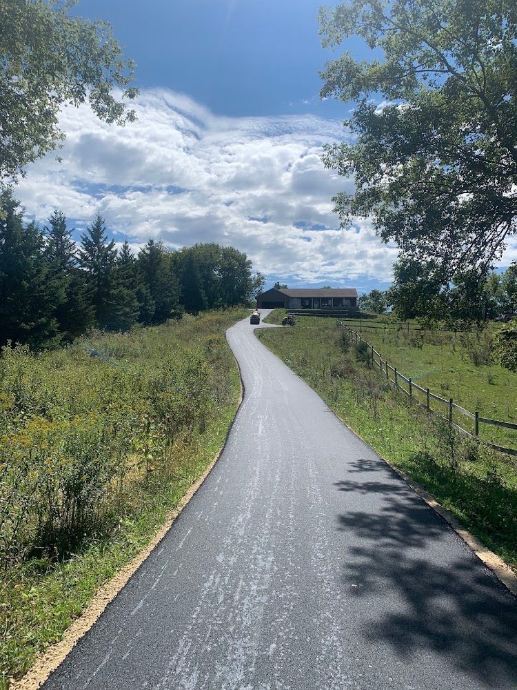 Tradesperson performing asphalt patching on a residential driveway in Northern Iowa.