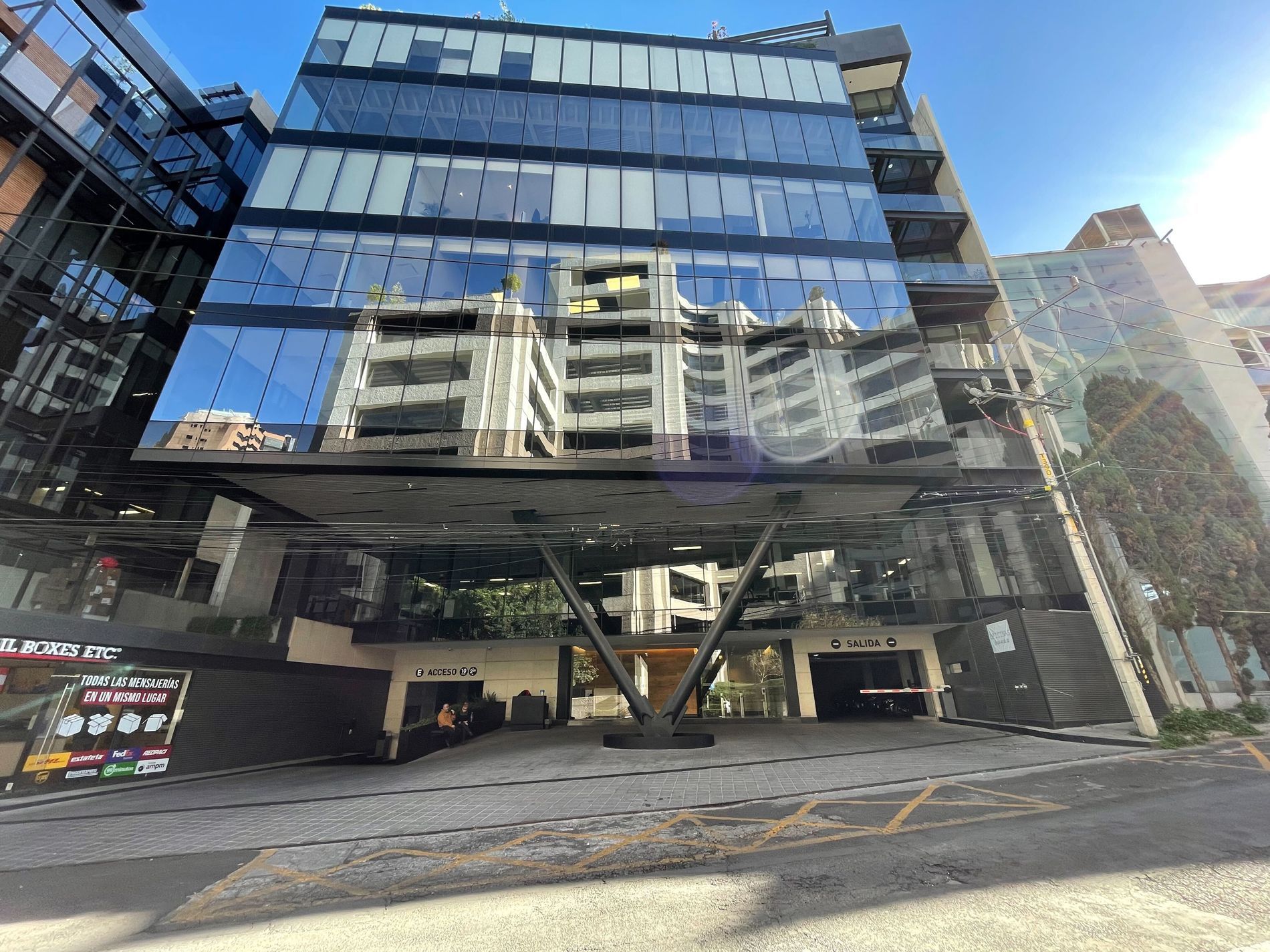 Un edificio grande con muchas ventanas y muchos autos estacionados frente a él.
