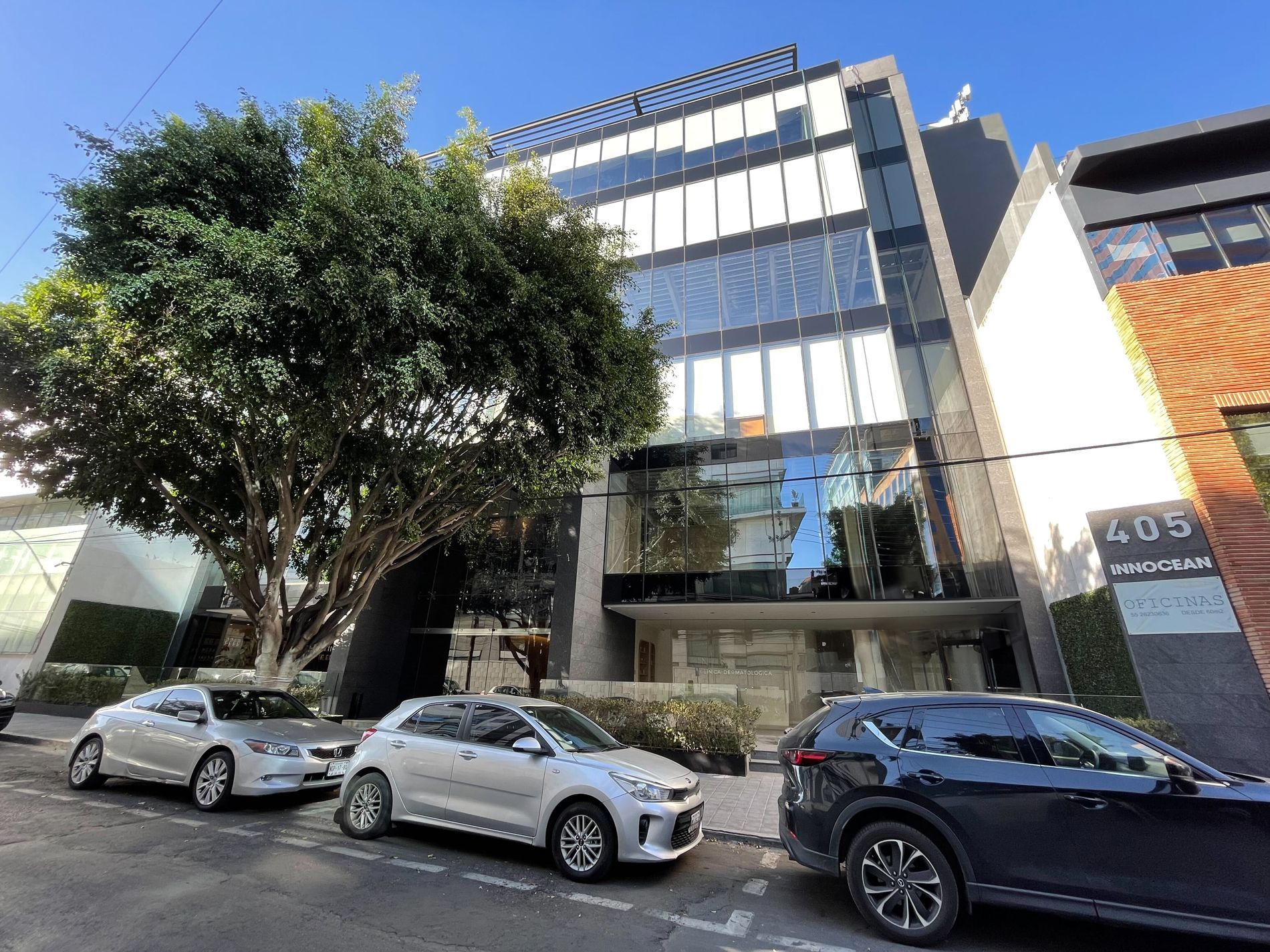 Un grupo de autos está estacionado frente a un edificio.