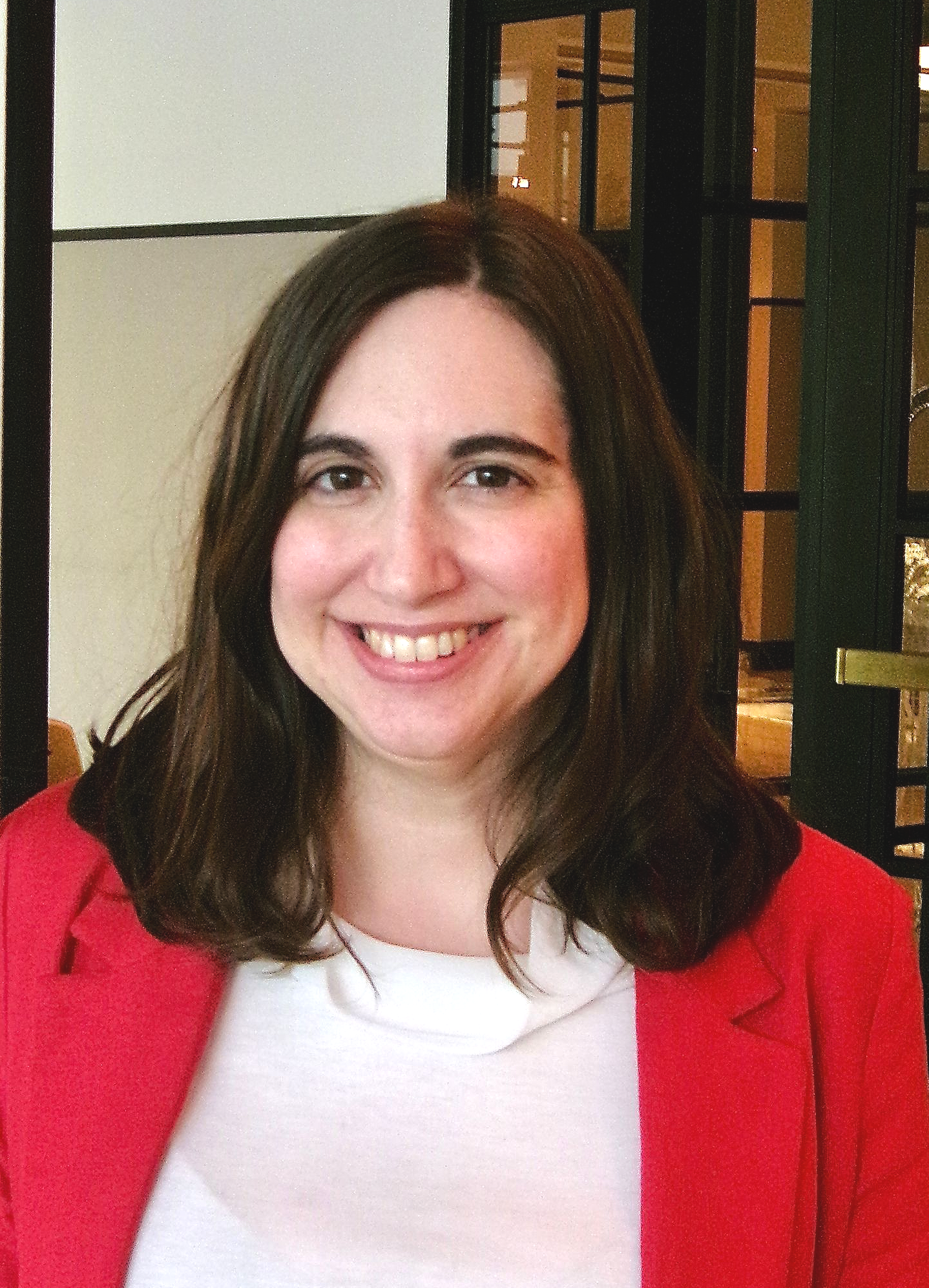 Woman in red blazer and white top smiles at camera.