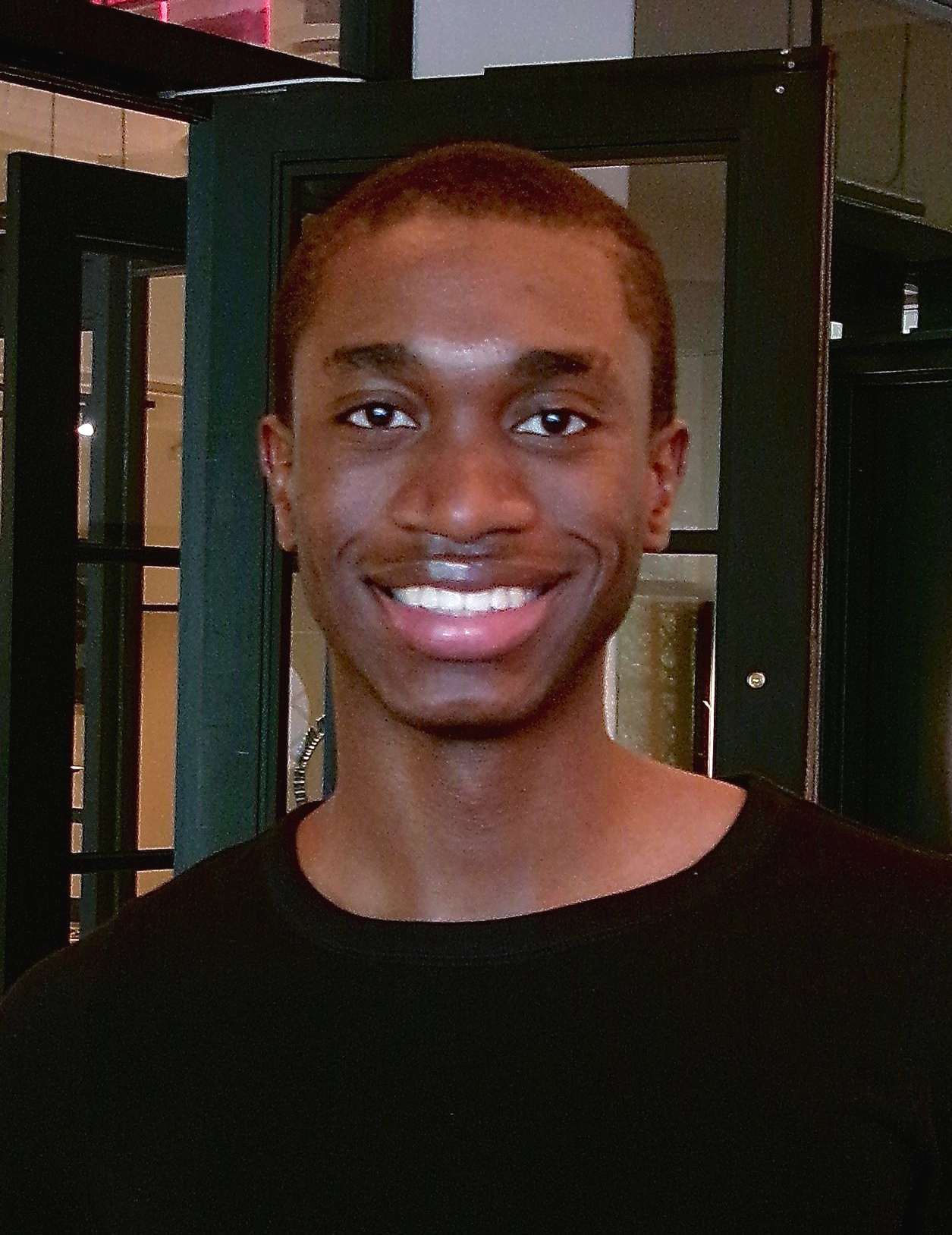 Dark haired man in black long sleeve shirt smiles at camera.
