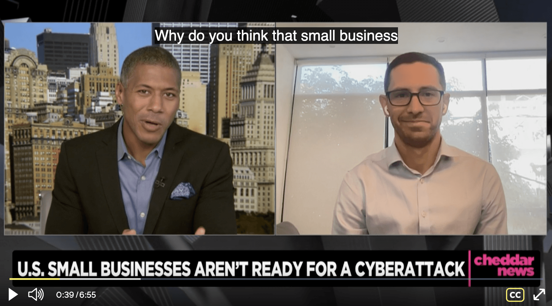 Two men in a studio; one interviewing the other about cybersecurity for small businesses, text overlay.