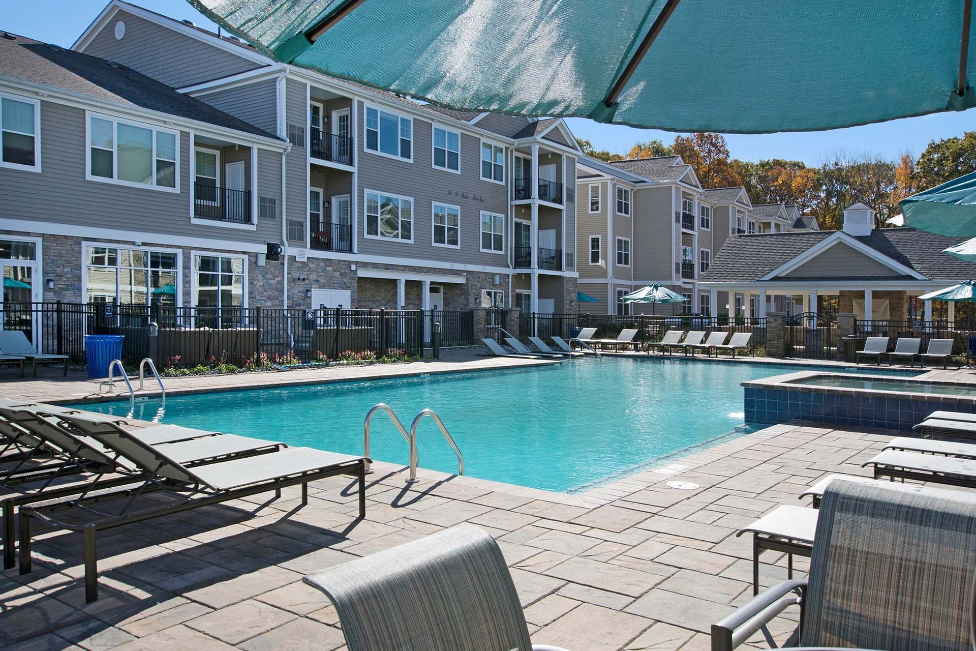 Outdoor pool area of apartment community with lounge chairs and buildings at The Parc at Roxbury in  Roxbury, NJ.