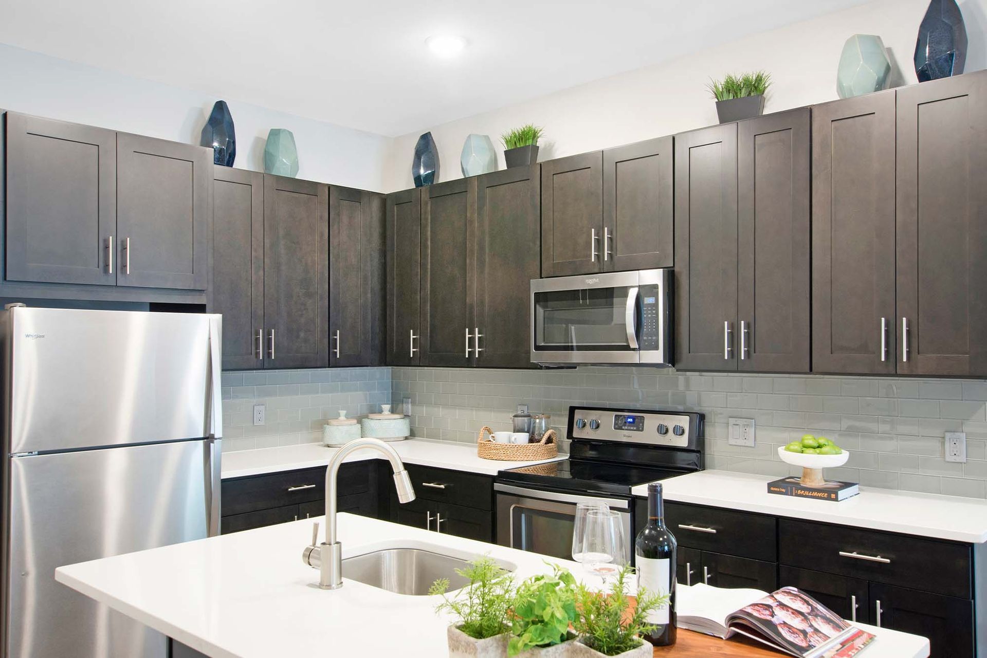 Modern kitchen with dark wood cabinets, stainless steel appliances, and a white island at The Parc at Roxbury in  Roxbury, NJ.