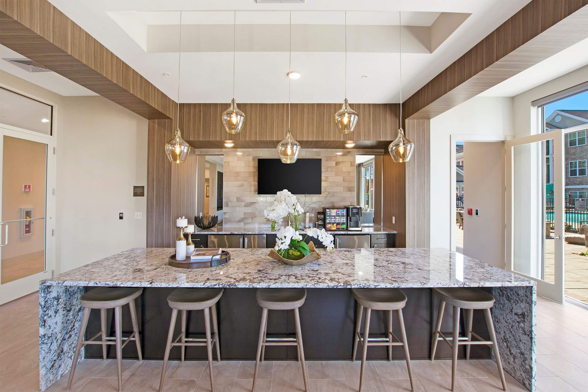 Open-concept community kitchen with marble island, pendant lights, and outdoor doors at The Parc at Roxbury in  Roxbury, NJ.