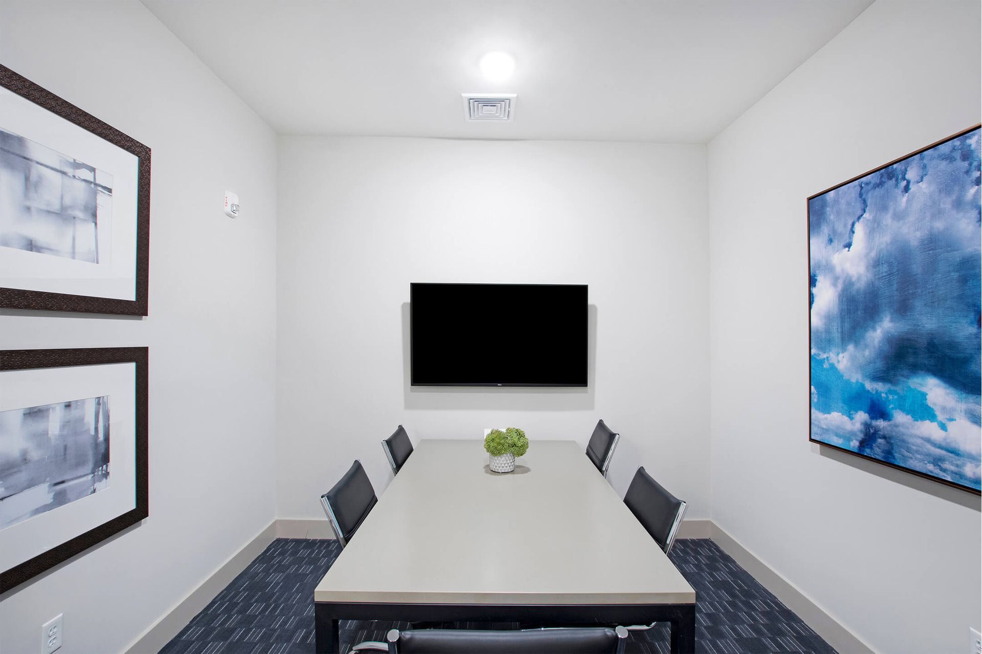 Conference room with a rectangular table, wall-mounted TV, chairs, and framed artwork at The Parc at Roxbury in  Roxbury, NJ.