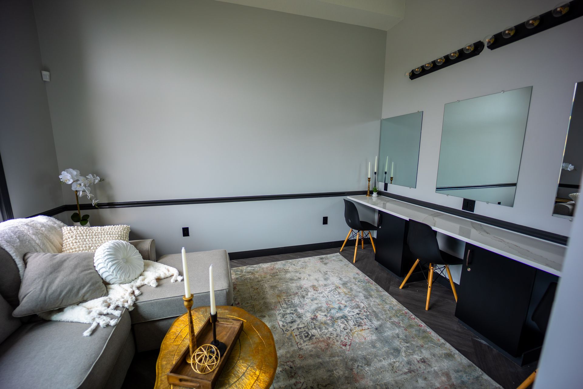 A living room with a couch , table , chairs and mirrors.