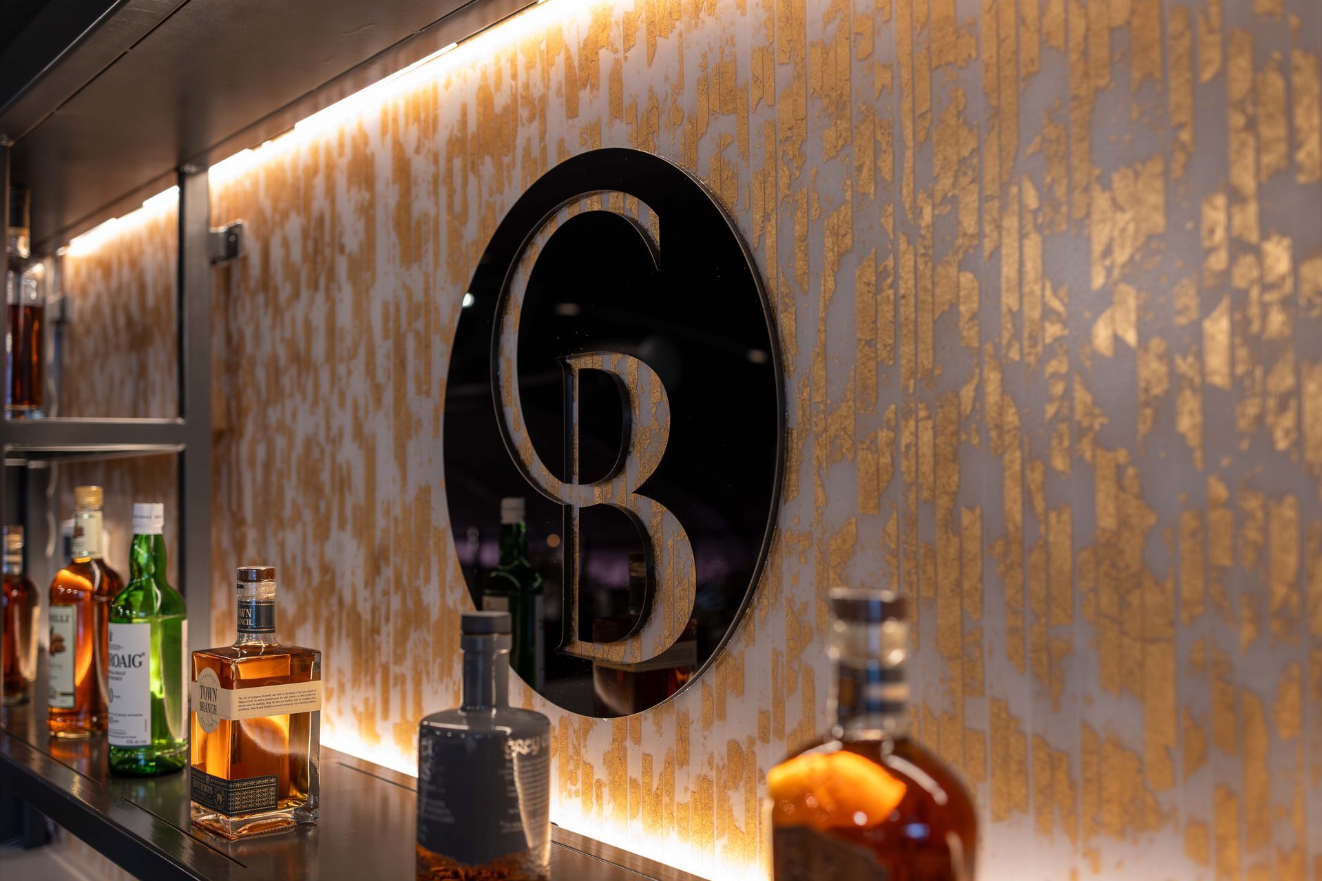 A bar with bottles of alcohol and a sign on the wall.