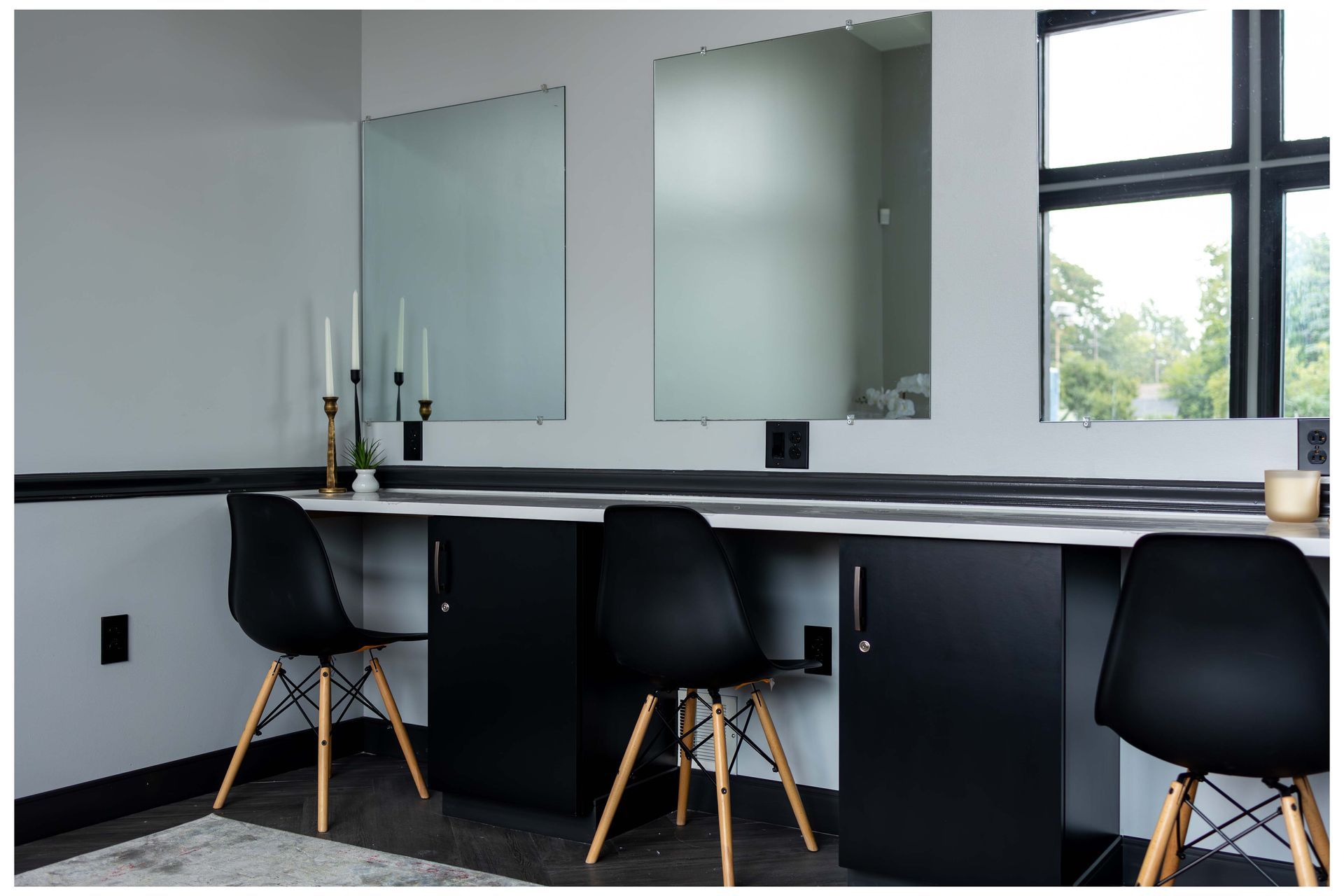 A room with two desks and two chairs and two mirrors on the wall.