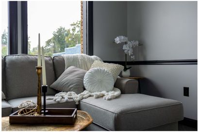 A living room with a couch , ottoman , candles and a window.