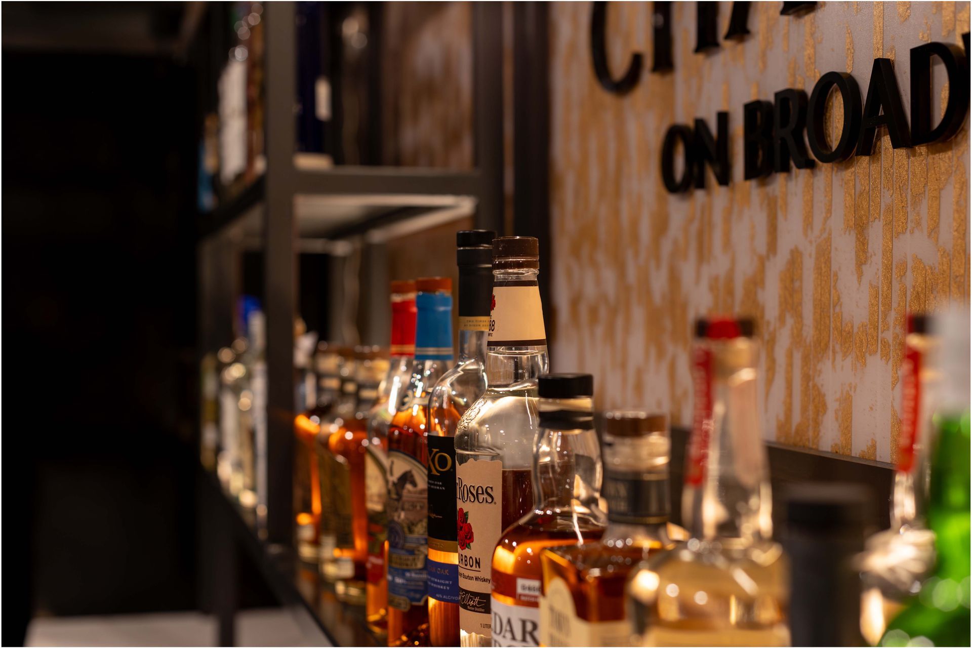 A row of bottles of liquor are lined up on a bar.