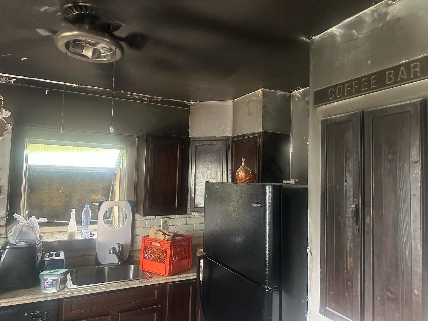 Dim kitchen with black cabinets, stainless fridge, and a coffee bar sign above a doorway