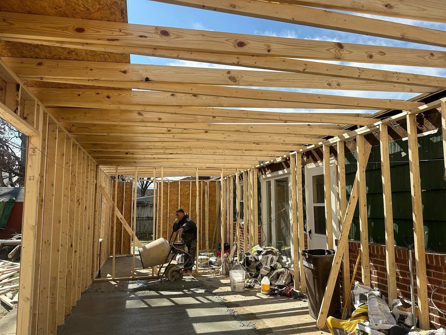 Wood-framed building under construction with exposed rafters and tools scattered on the floor
