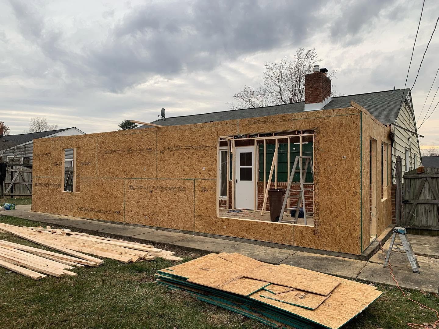 Partially built brick house with scaffolding and plywood on a cloudy construction site