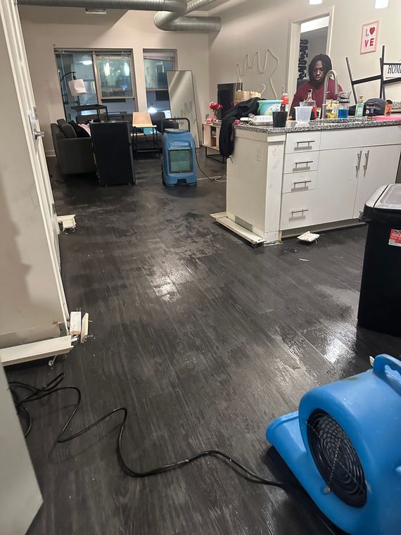 Hair salon interior with styling stations, mirrors, counters, and blue floor fan on a dark floor