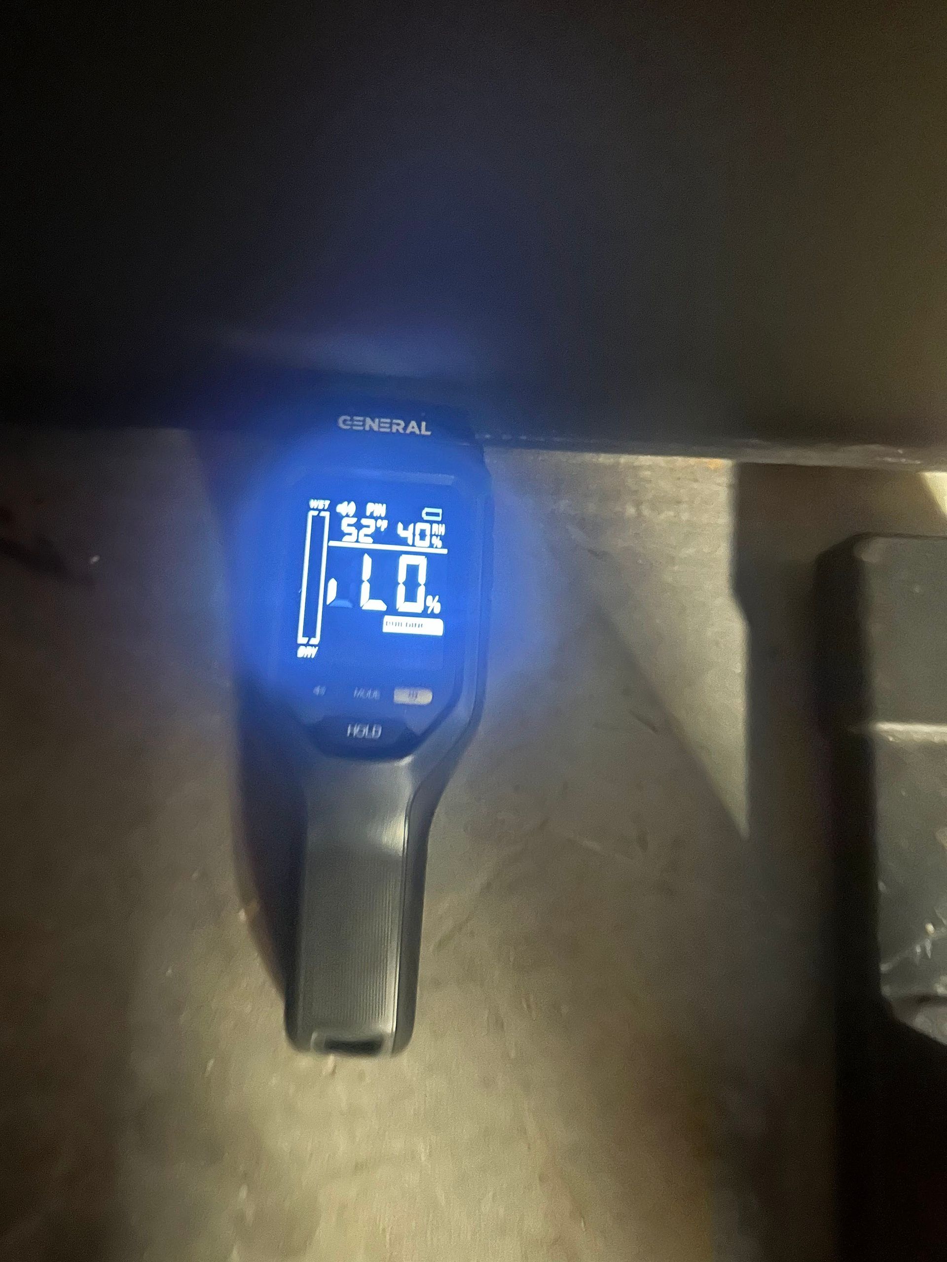 Glowing blue digital device display mounted on a dark surface, showing temperature and status icons.