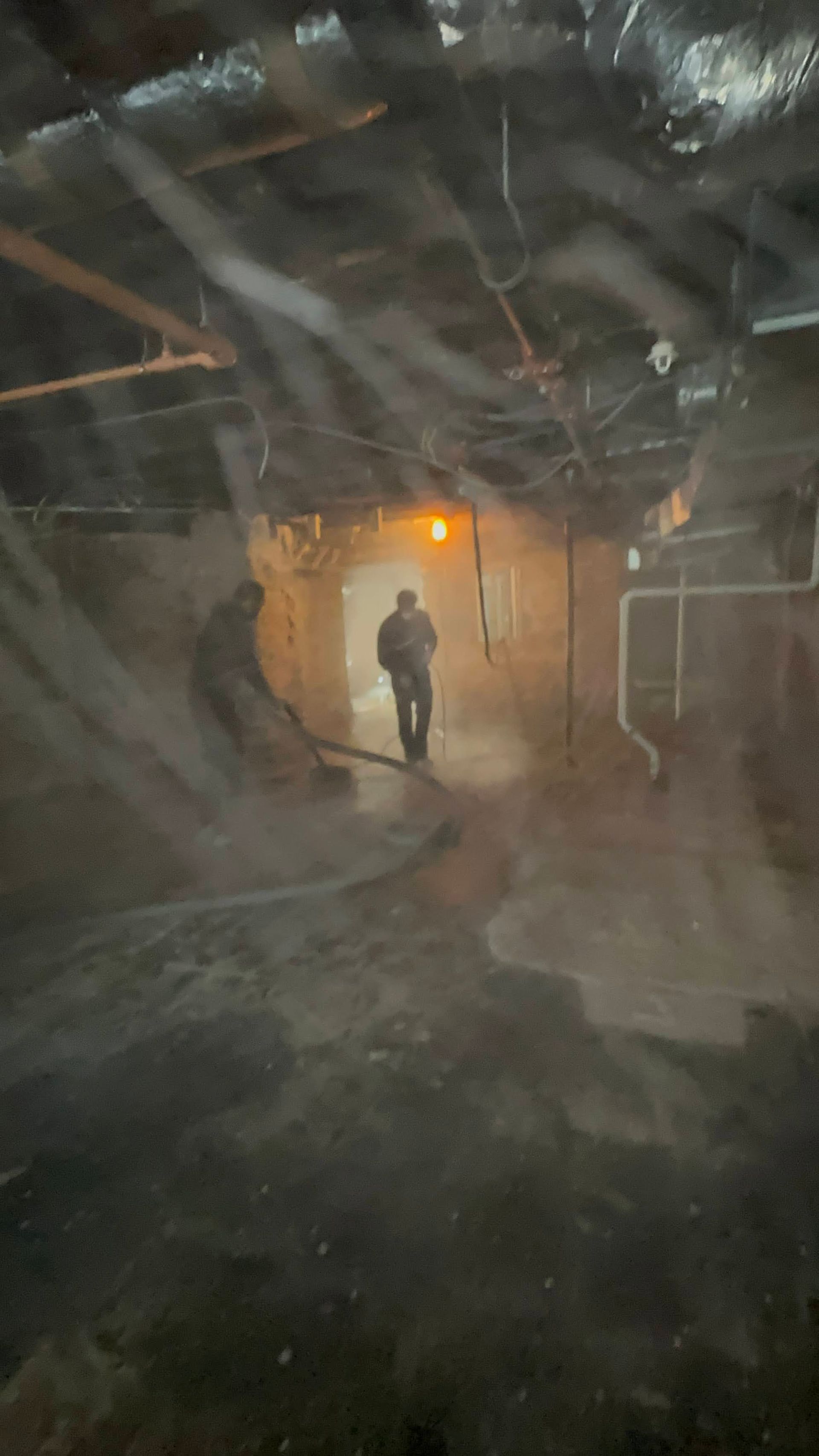 Person walking through a smoky, dimly lit tunnel with an orange light in the background