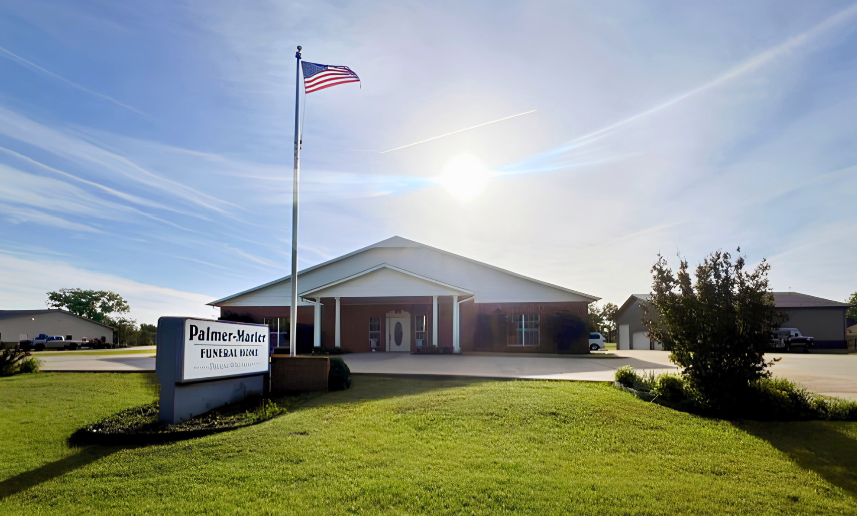 Brick building with American flag and sign reading “Palmer-Marler” on a sunny lawn.