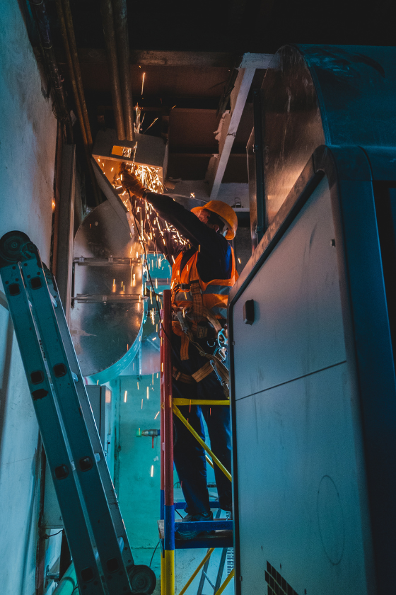A man is standing on a scaffolding working on a ceiling.