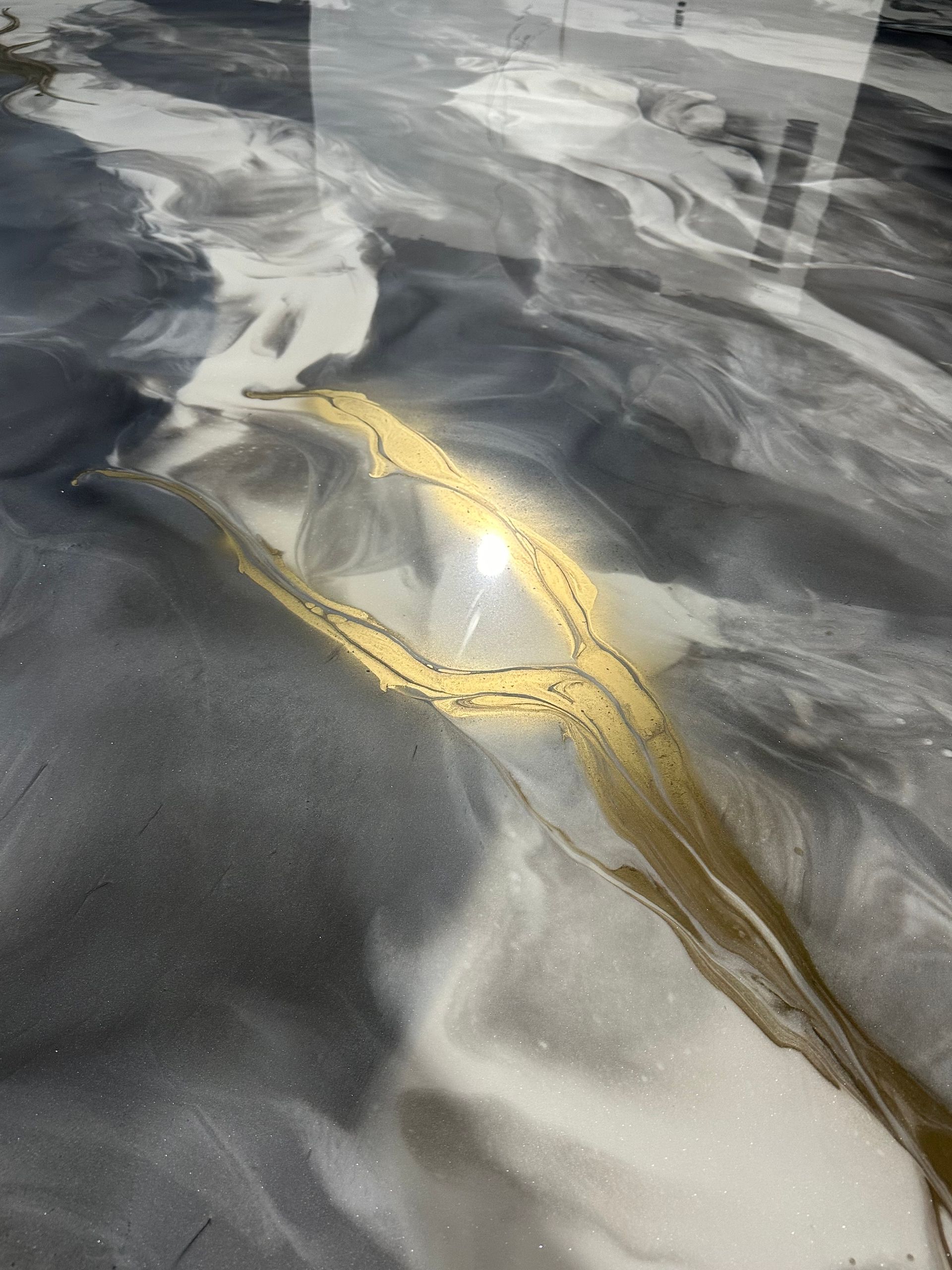 Gros plan sur une surface en marbre gris brillant veinée de blanc et rehaussée d'un liseré doré.
