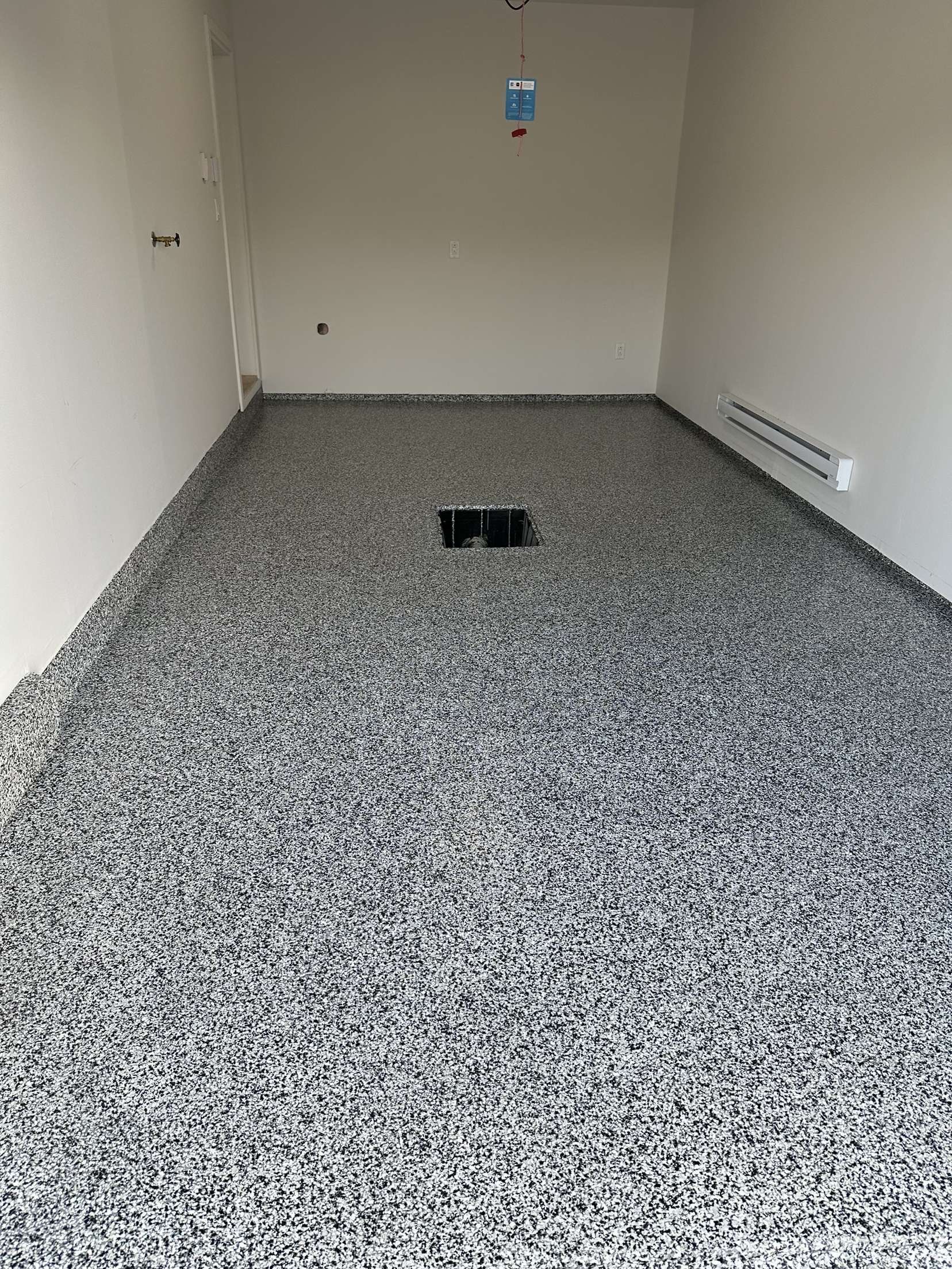 Une grande pièce vide avec un sol gris et des murs blancs.