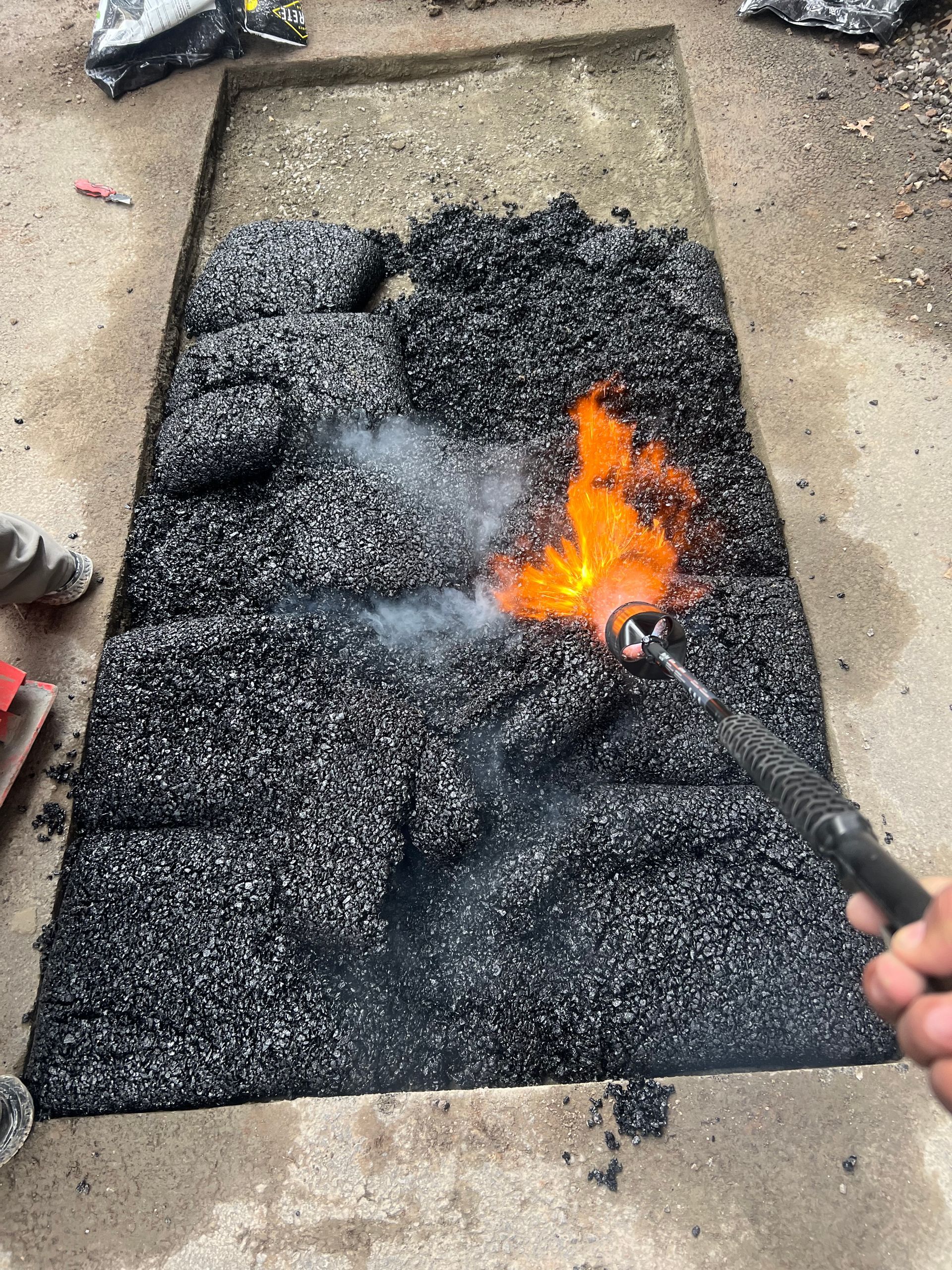 Worker applying a flame torch to black roofing material on a flat surface. Worker applying a flame torch to black roofing material on a flat surface.