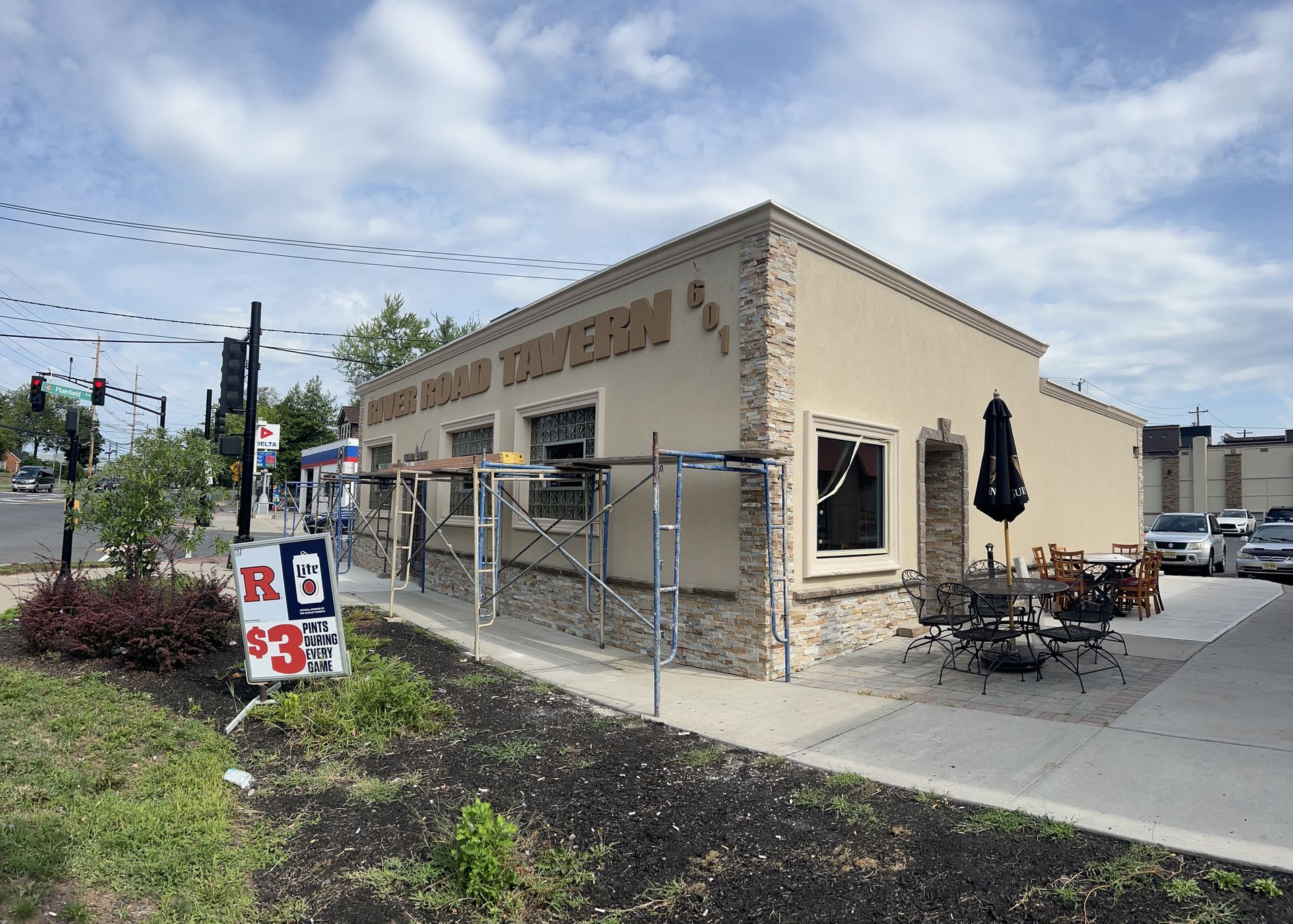 Corner cafe with outdoor patio seating, tan stucco exterior, and a street-side sign on a cloudy day Corner cafe with outdoor patio seating, tan stucco exterior, and a street-side sign on a cloudy day