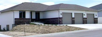 Single-story suburban house with a gray roof, white exterior, and two garage doors.