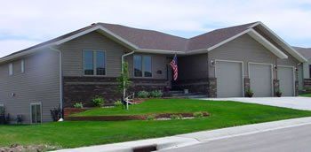 Suburban single-story house with gray siding, two-car garage, and a manicured lawn