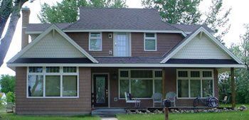 Two-story brick house with white trim, front porch, and gabled roof in a suburban yard
